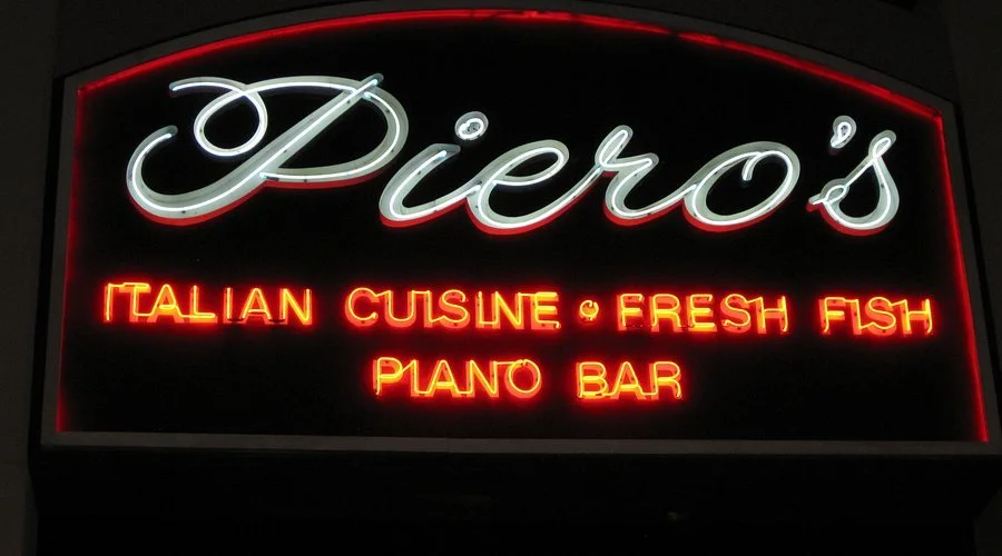 Neon sign for Piero's restaurant with the text 'Italian Cuisine & Fresh Fish Piano Bar'.