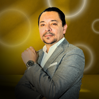 Hombre de negocios con traje gris y fondo dorado con círculos luminiscentes.