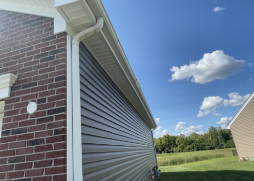 Beige vinyl siding and gutter installed on a brick home