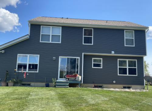 Rear view of a home with new blue siding and replacement windows