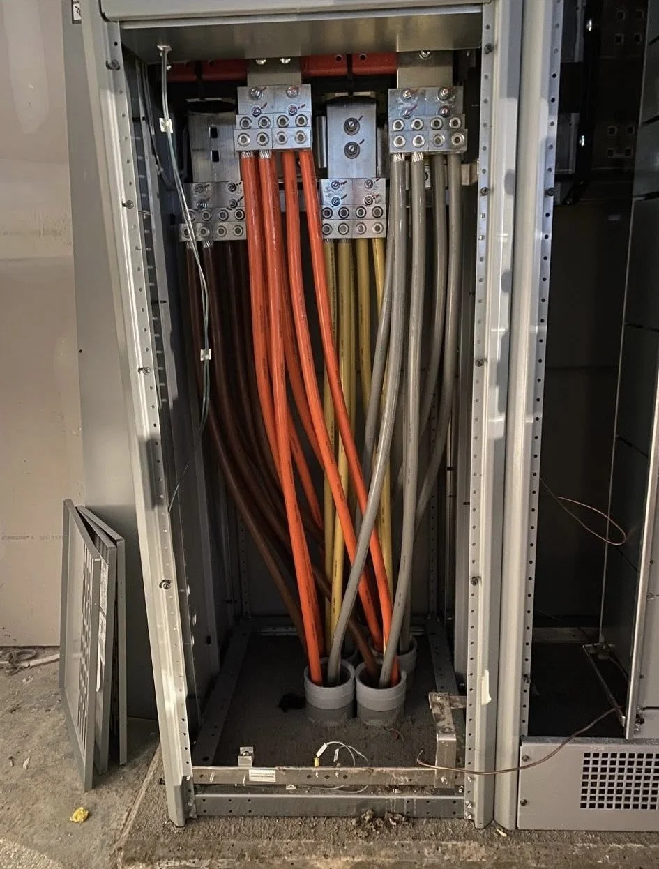 Electrical panel with colorful insulated wires connected to silver terminal blocks inside a metal cabinet.