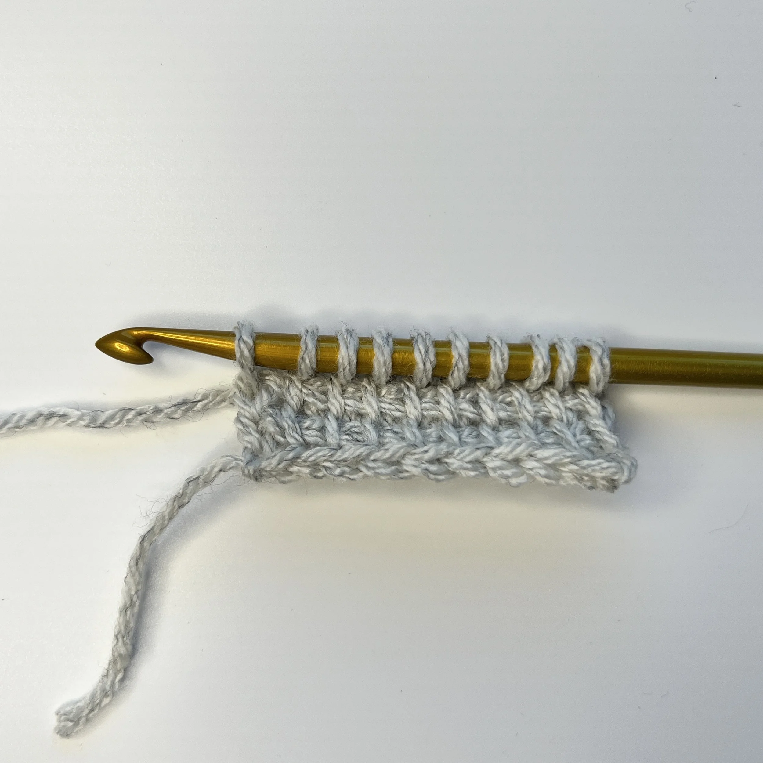 Start with a base of Tunisian simple stitches. My sample has 10 ch and 10 tss x 2 rows. 
Short Row FP: Worked as a normal tss row – Tss to end, pick up loop in edge st – 10 loops on hook.