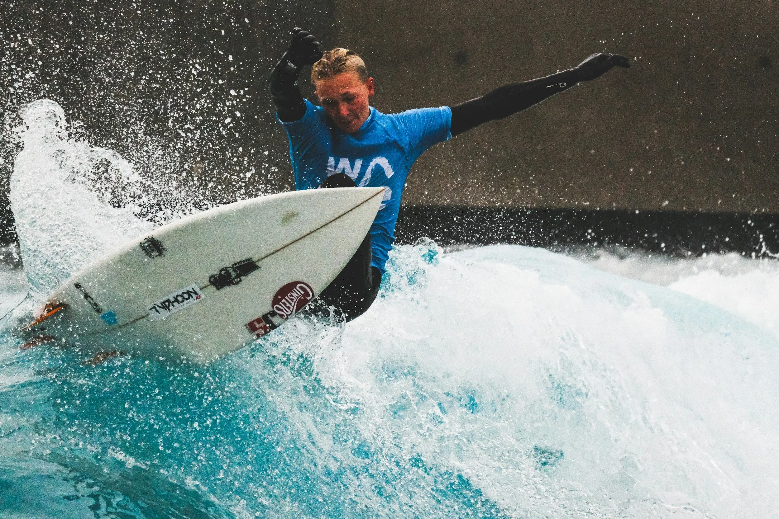 A person surfing on a wave in the ocean, with focus on the surfer's concentrated expression and splash of water around them.