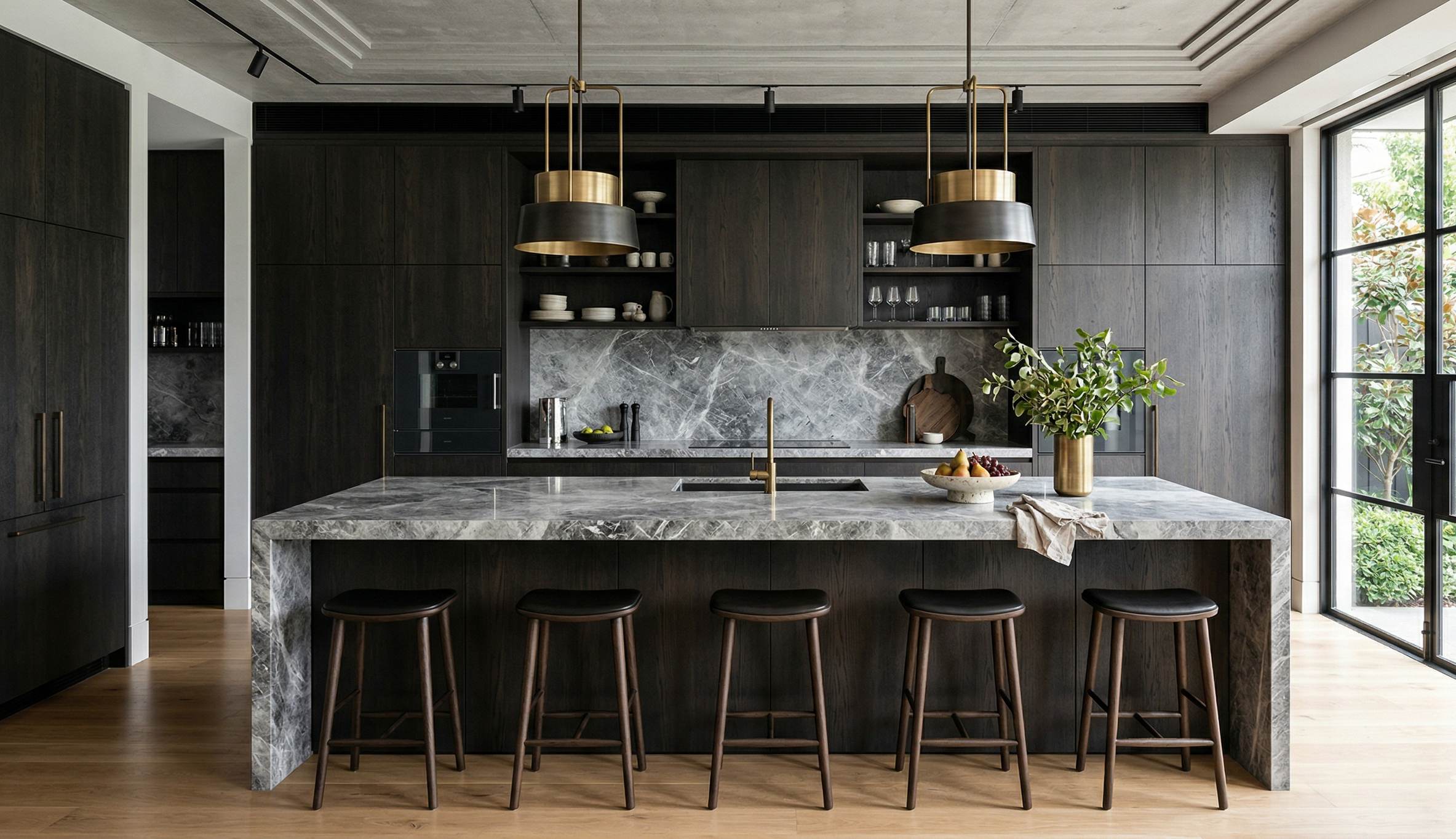 Modern black and gray kitchen with marble island, dark wood cabinets, pendant lights, and large windows with outdoor view.