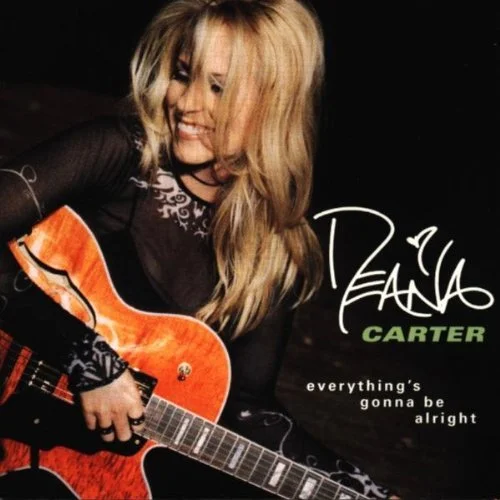 Woman with long blonde hair smiling and playing an orange guitar, wearing a black top with lace detail, with text reading "Diana Carter, Everything's Gonna Be Alright."