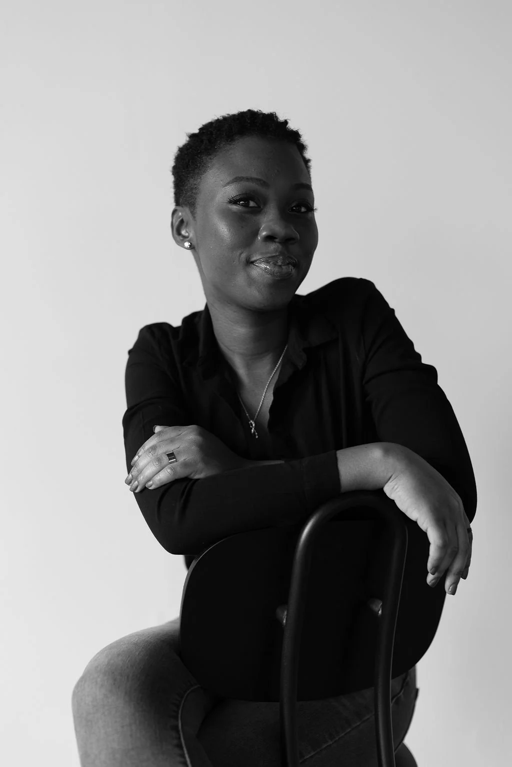 Black and white portrait of Veronica Dogbegah, sitting with arms crossed, looking at the camera.