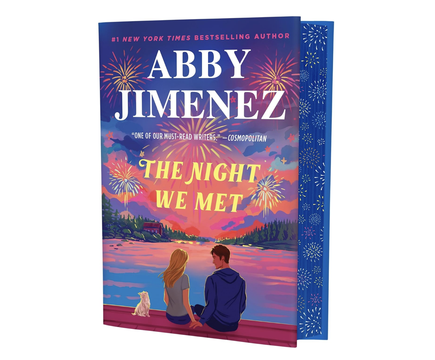Cover of the book titled "The Night We Met" by Abby Jimenez, featuring an illustration of a sunset over a lake with fireworks, a woman and a man sitting on a dock, and a dog sitting beside them.