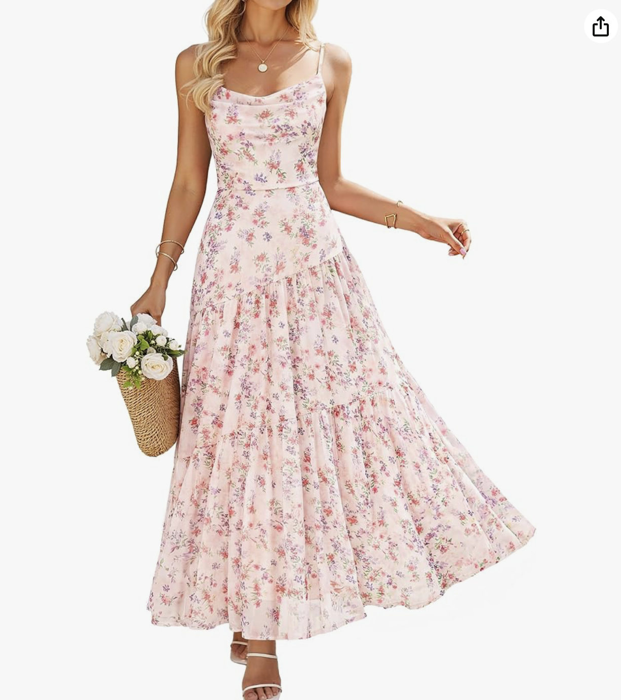 A woman wearing a sleeveless pink floral maxi dress, holding a basket of white roses, and standing against a plain light background.