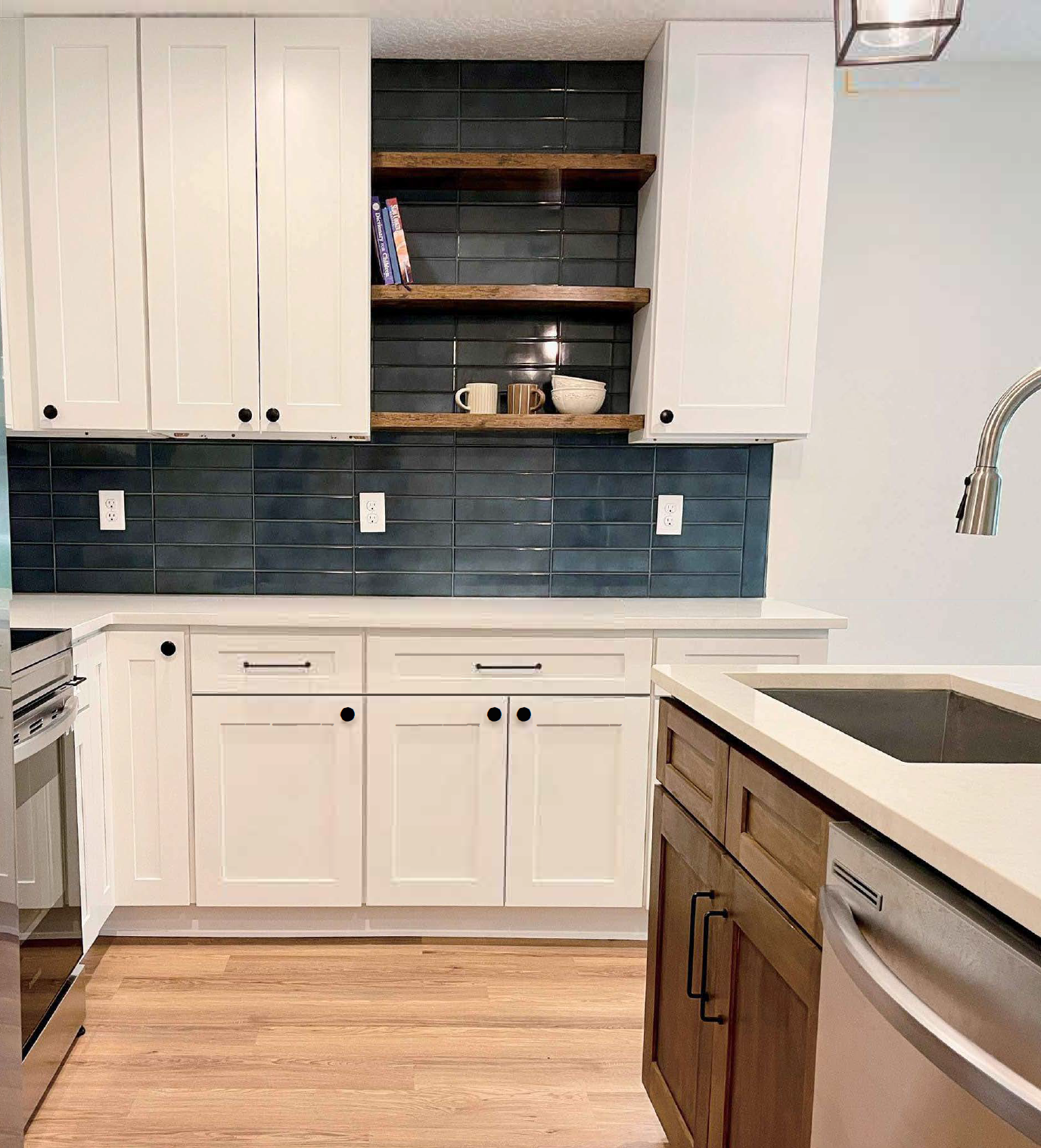 Modern kitchen with white cabinets, open wooden shelves with dishes, dark tiled backsplash, light wood flooring, and a kitchen island with a sink and a dishwasher.