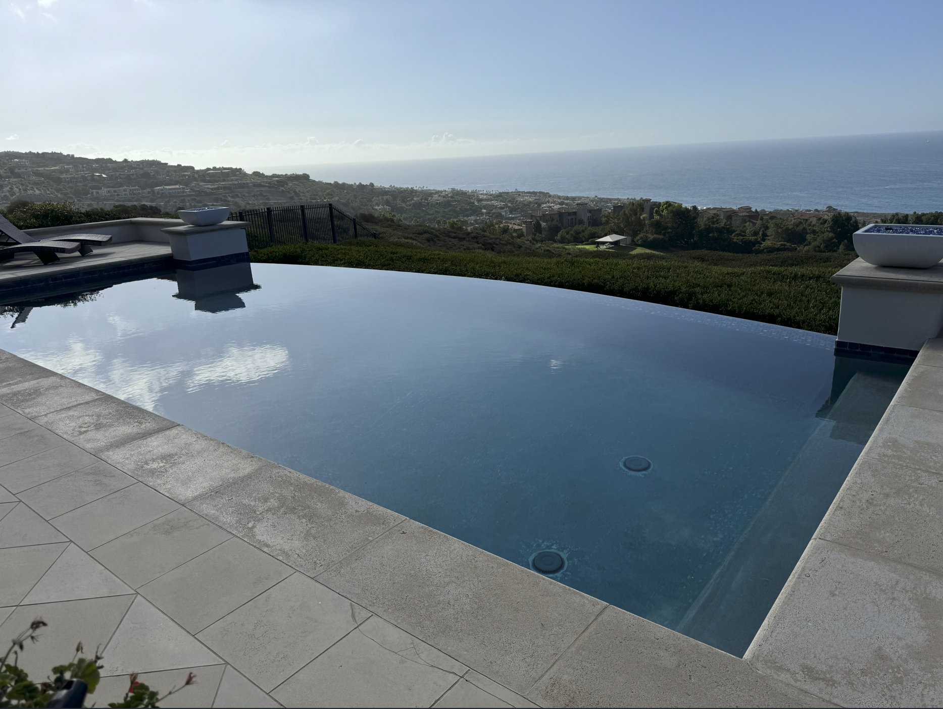 An infinity pool overlooking a hilly landscape with the ocean in the background.