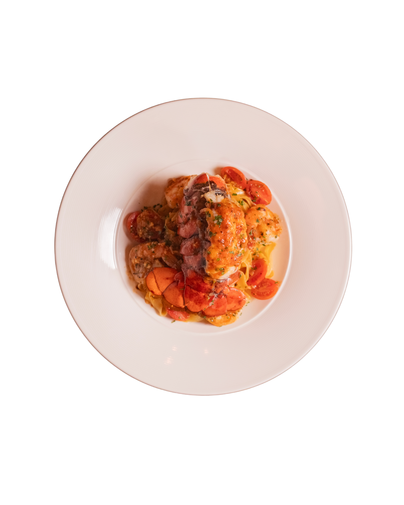Plate of cooked pasta with cherry tomatoes, topped with a piece of cooked lobster or seafood, garnished with herbs.