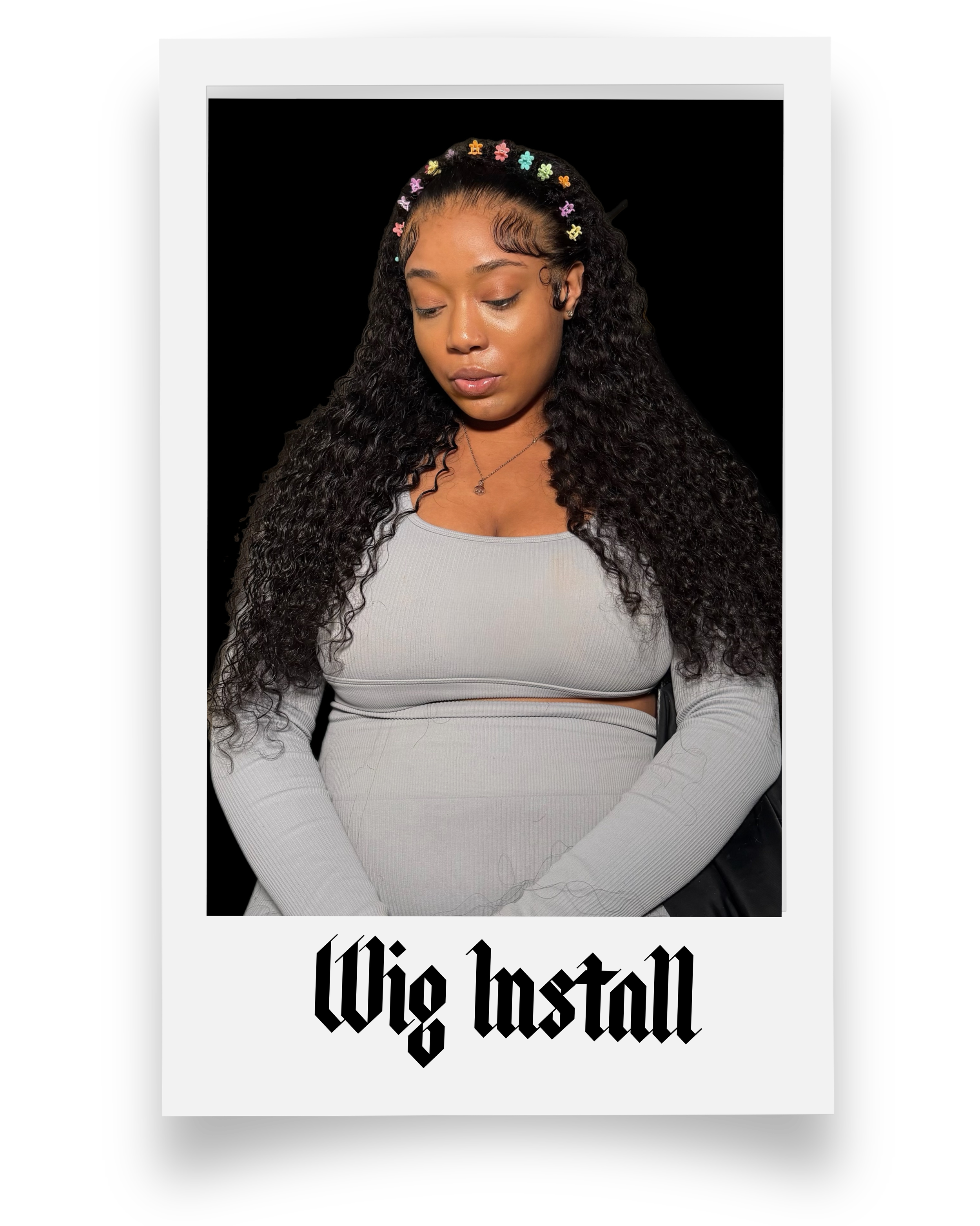 A young woman with long curly hair and a colorful floral headband, wearing a light gray long-sleeve top, looking downward with a neutral expression, against a black background with a white border and the phrase "Wig Install" in bold black gothic font at the bottom.