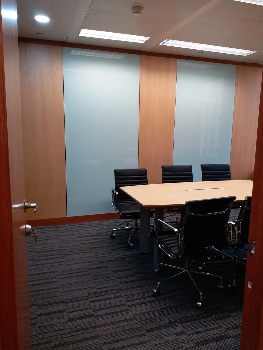Executive meeting room enclosed by full-height glass wall with warm wooden accents, offering privacy and visual transparency.
中文: 高級會議室，以全高玻璃隔間結合溫暖木質元素，既保障私密性，又保持視覺通透感