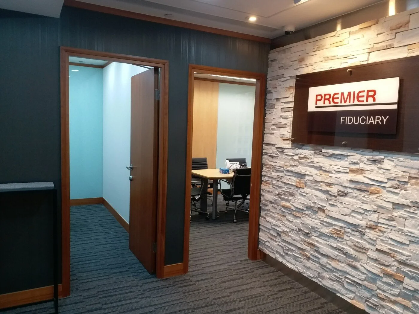 Sophisticated reception area with textured stone wall and custom PREMIER signage, creating a refined and welcoming corporate entrance.
 精緻接待區，以質感牆搭配訂製 PREMIER 標誌，打造優雅專業的企業迎賓空間
