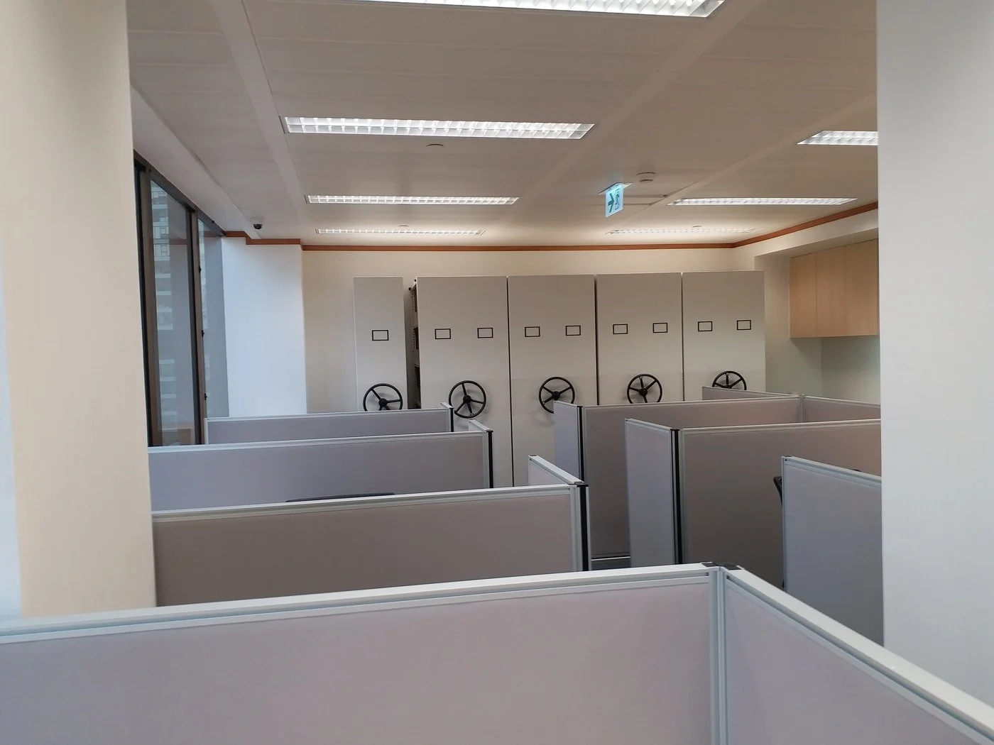 Bright open-plan office with ergonomic cubicles and expansive city views through large windows.
 明亮開放式辦公區，人體工學隔間設計搭配大面窗戶，享有開揚城市景觀。