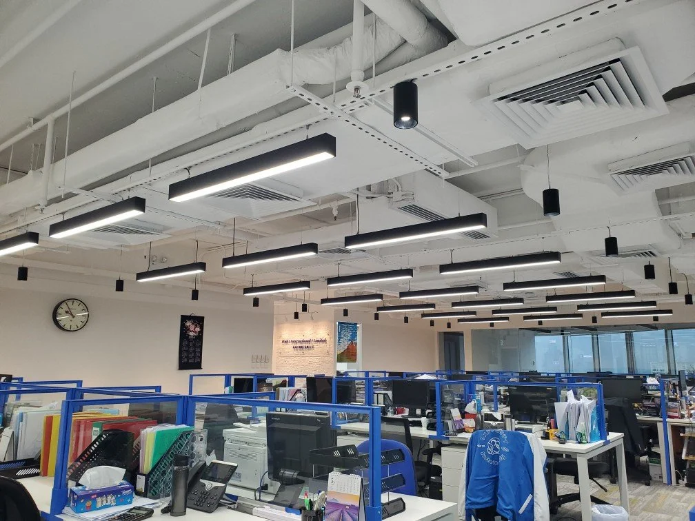 Dynamic open-plan office with industrial-style pendant lighting and vibrant blue workstations.
活力開放式辦公區，工業風吊燈搭配鮮藍色工作站，展現現代高效的工作環境