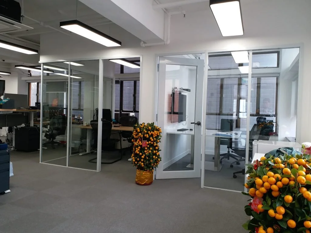 Bright open-plan office with full-height glass partitions creating a fresh and welcoming workspace.
中文: 明亮開放式辦公區，全高玻璃隔間，營造清新宜人的工作環境