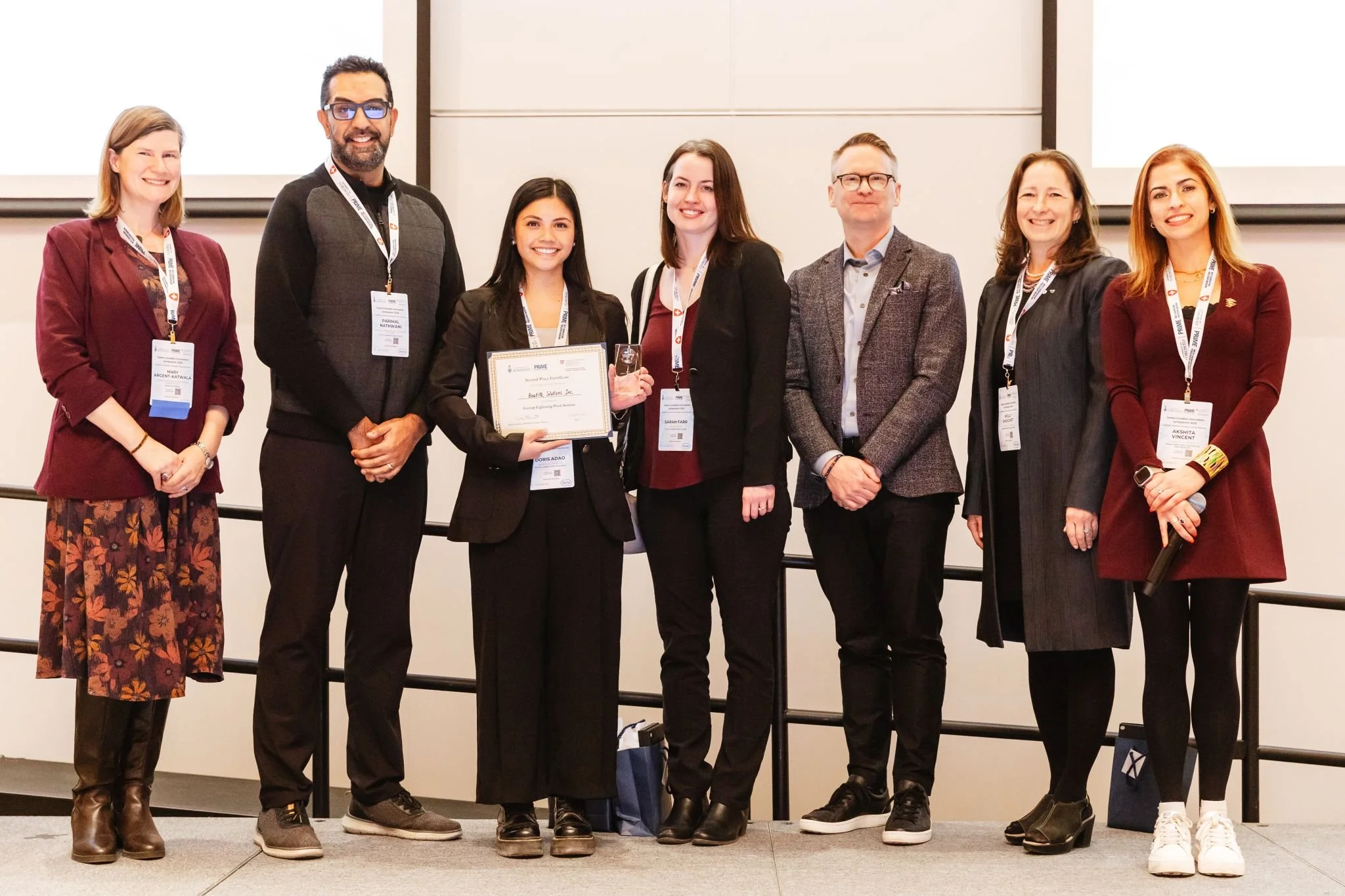 Group photo with a boutIQ member holding a certificate in the center, with several others standing on either side.