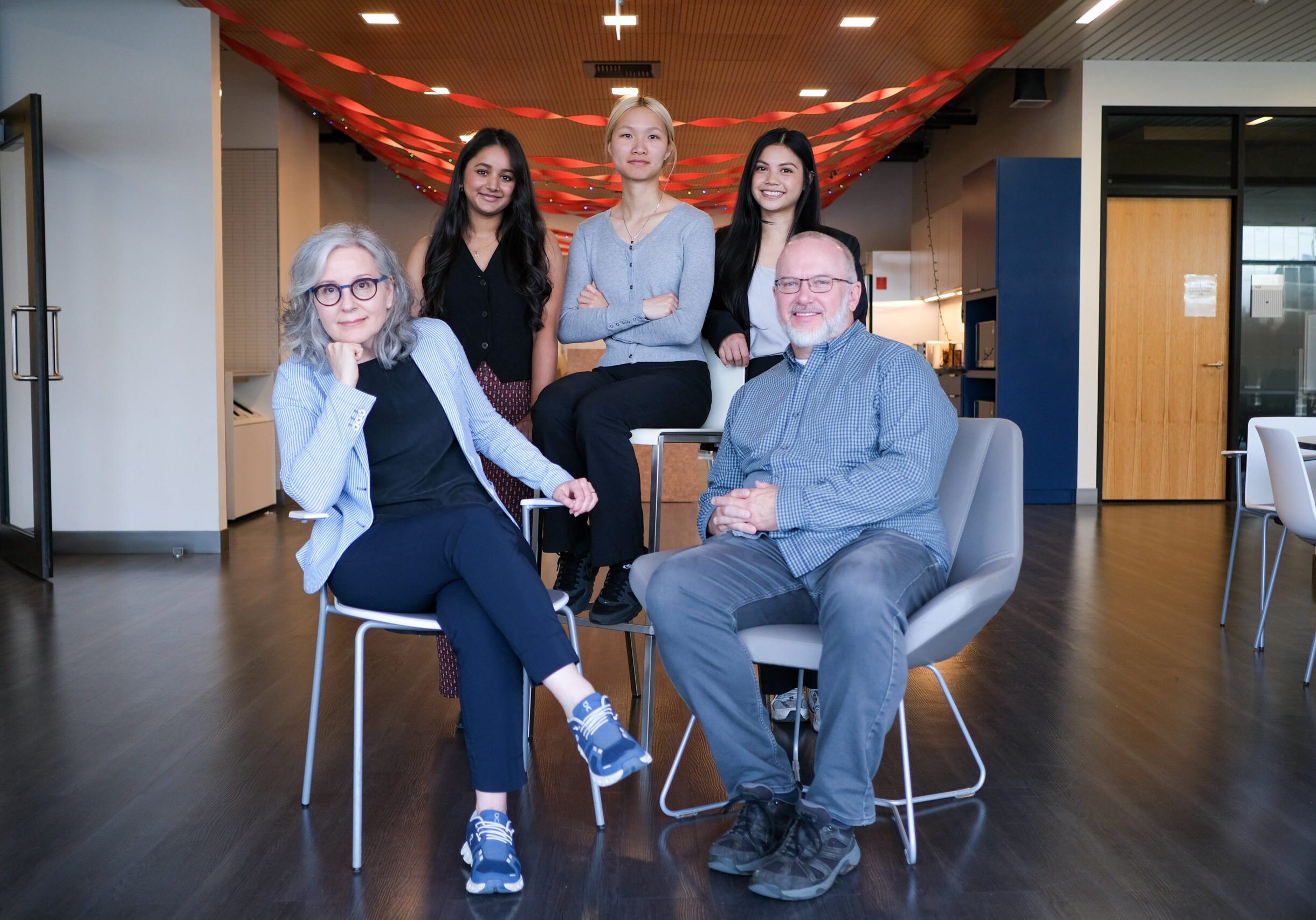 boutIQ teams group photo, three women standing behind seated men on the right and seated women on the left