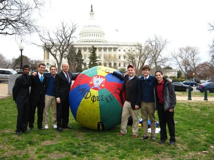 GW ZBT brothers with Representative Jim McGovern standing on grass in front of the U.S. Capitol, alongside our philanthropic ball.