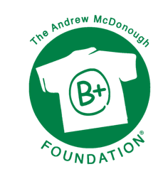 Logo of The Andrew Modonough Foundation featuring a black T-shirt with a B+ grade inside a circle and the foundation name around it in green.