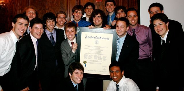 Fraternity brothers with a Zeta Beta Tau framed document.