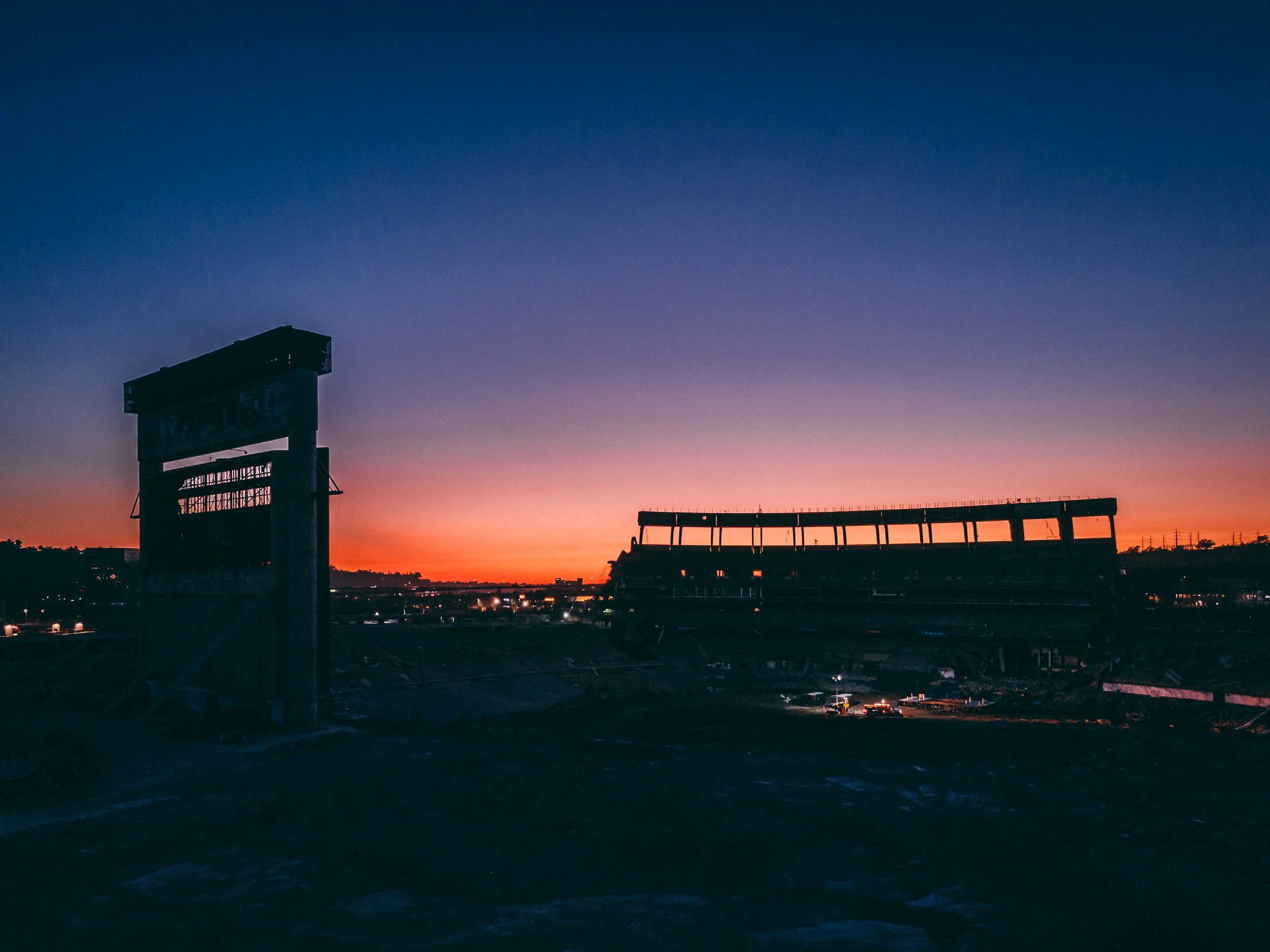 Silhouette of Qualcomm Stadium during its final days and a San Diego sunset with vibrant orange and purple sky in the background.