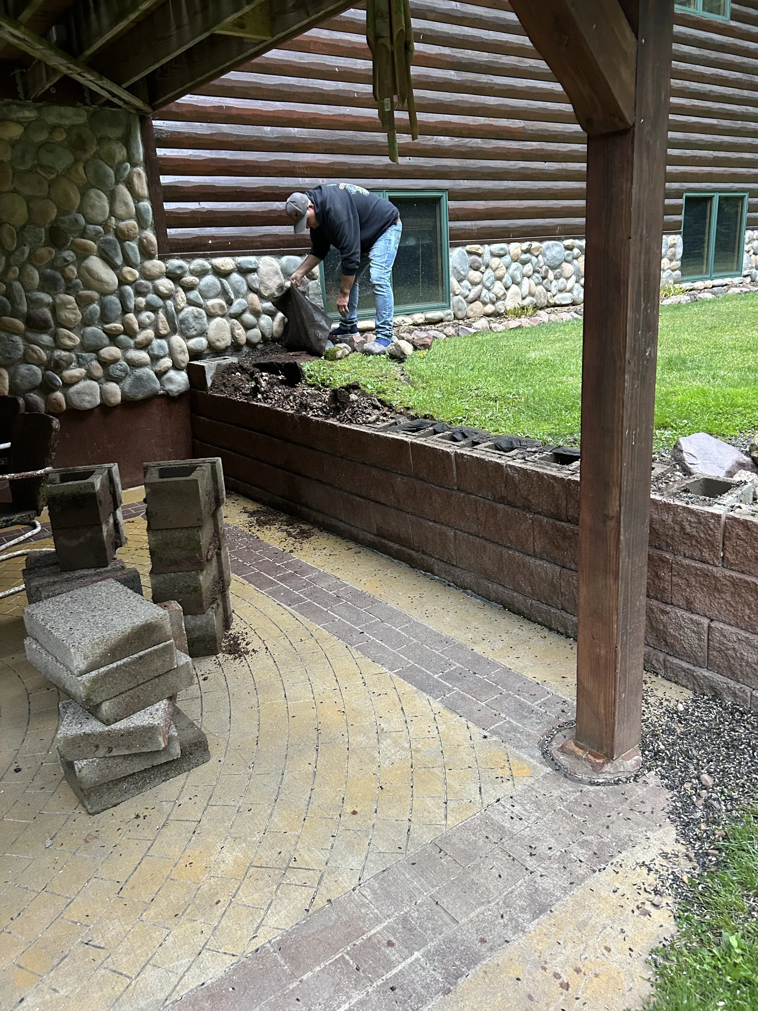 Person working on building a stone retaining wall outside a house