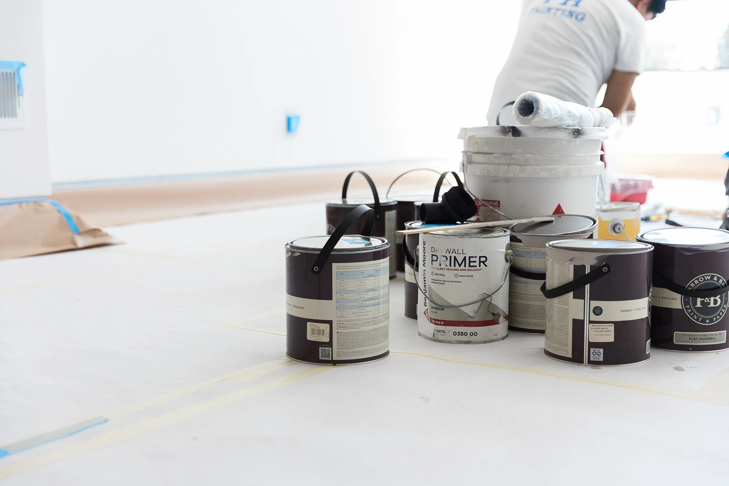 Paint cans and supplies on a table during a painting project at a construction site.