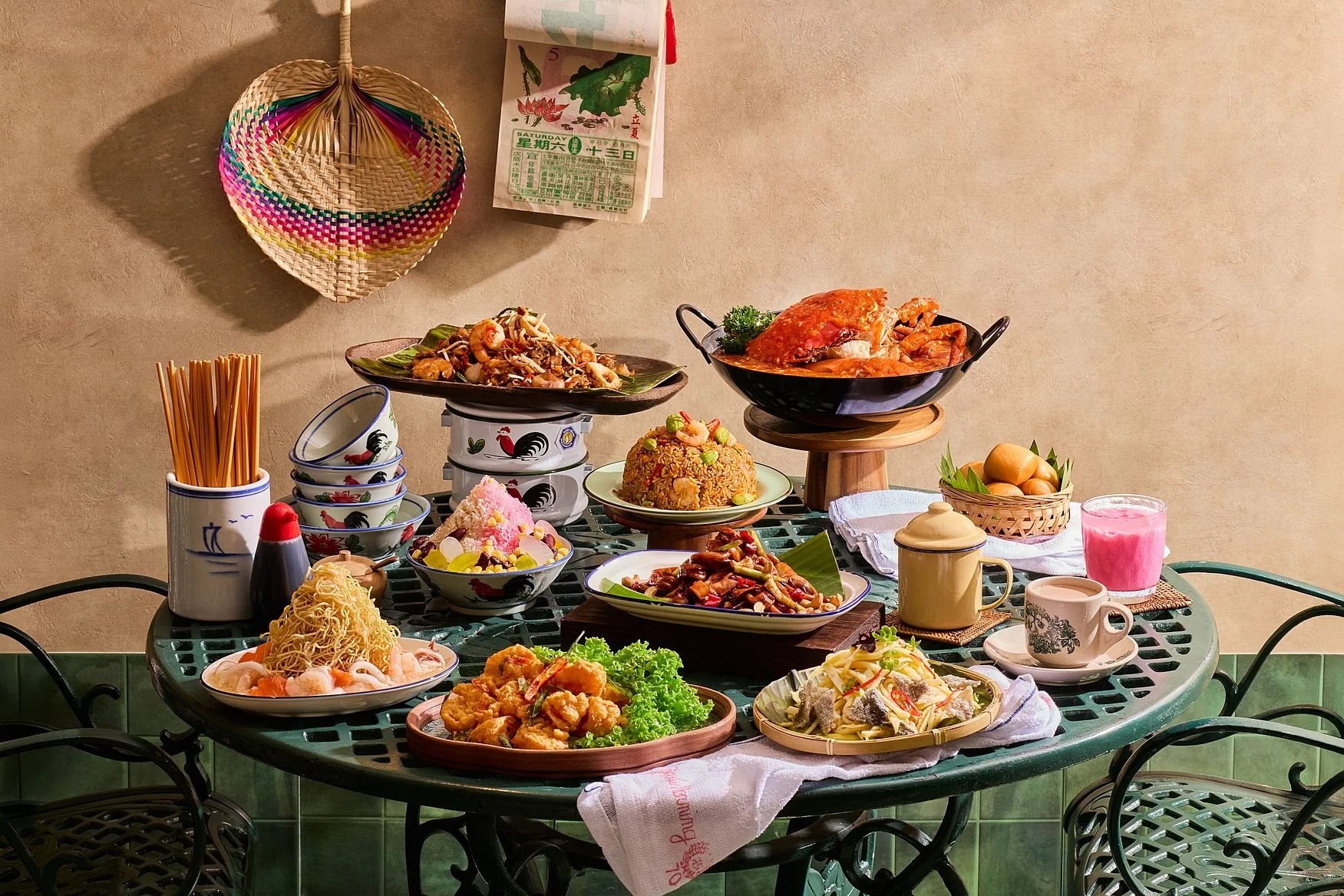 A table filled with various Asian dishes, including rice, noodles, seafood, chicken, and vegetables, with bowls, cups, and drinks on a green metal table.
