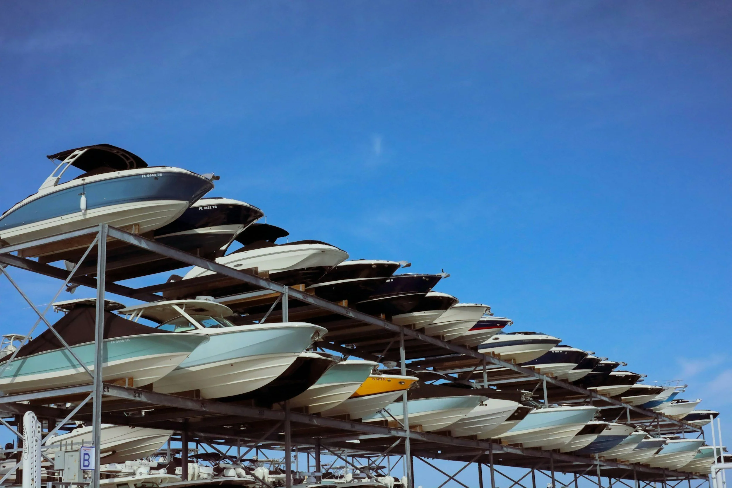 Rows of recreational boats stacked on storage racks beneath a clear blue sky