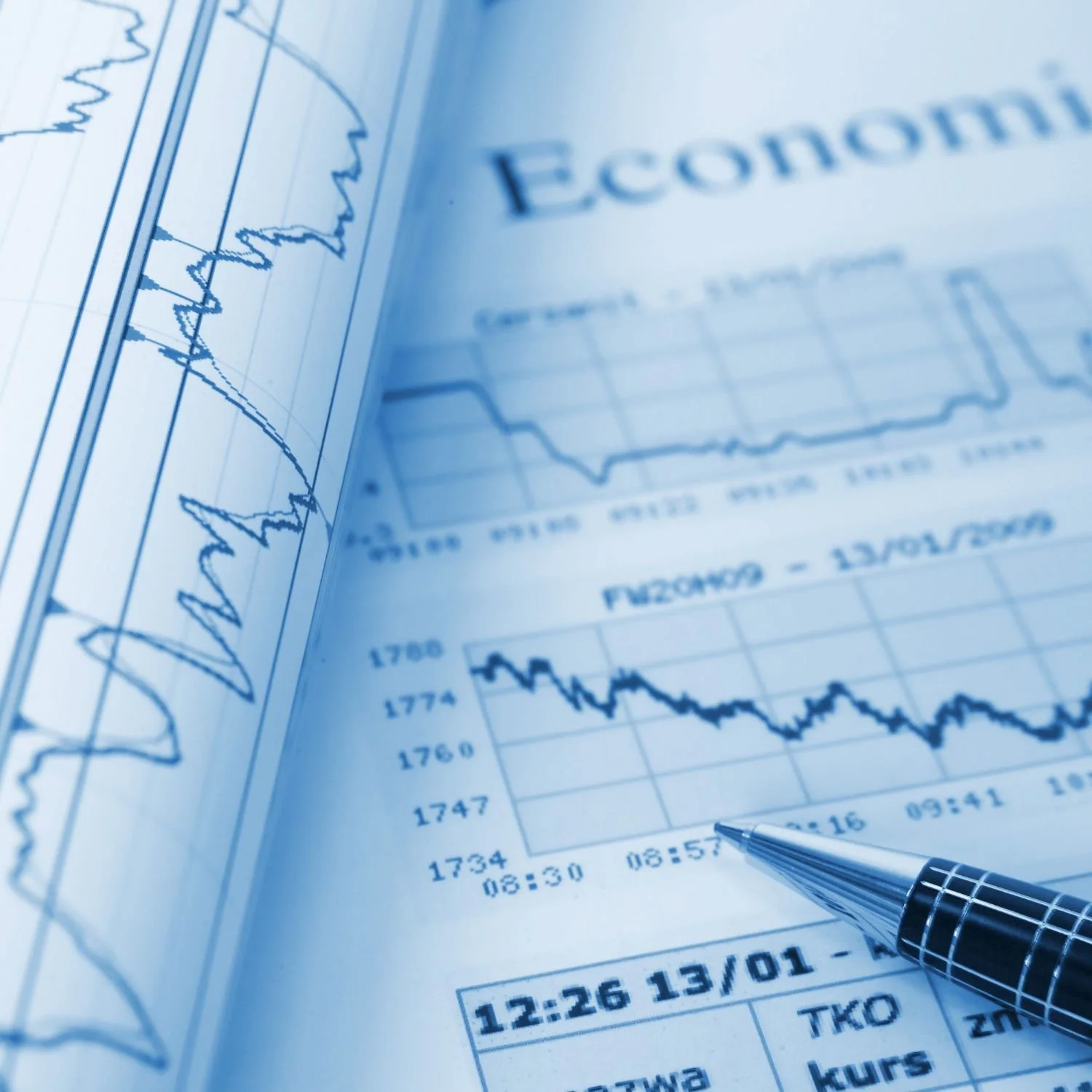 Close-up of economic charts and financial data on paper with a pen