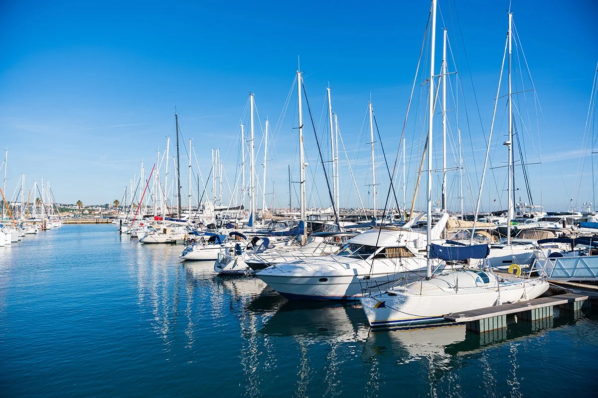Sailboats and yachts docked in a marina under a clear blue sky