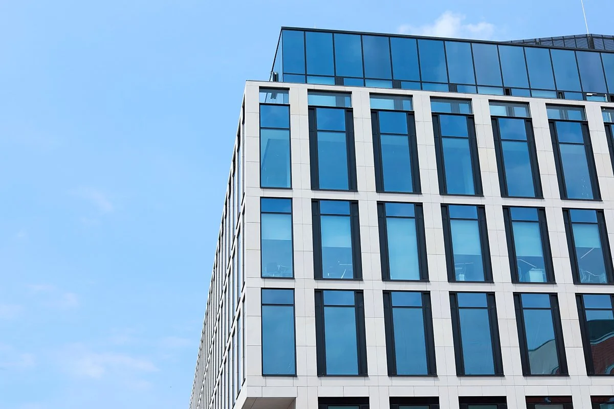 Modern office building with reflective blue windows and white facade against a clear blue sky
