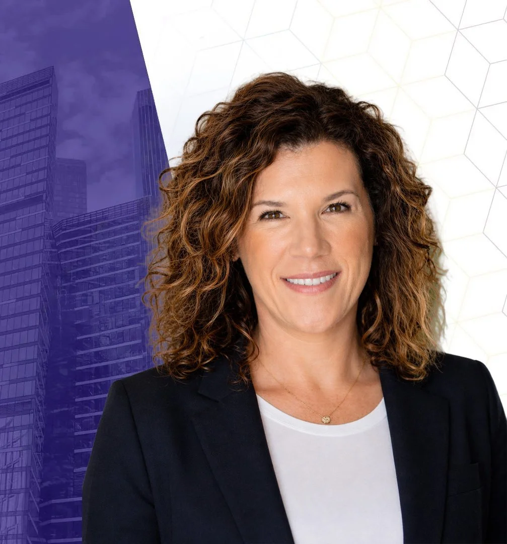 Professional headshot of a smiling woman with curly brown hair wearing a black blazer and white top against a purple cityscape background
