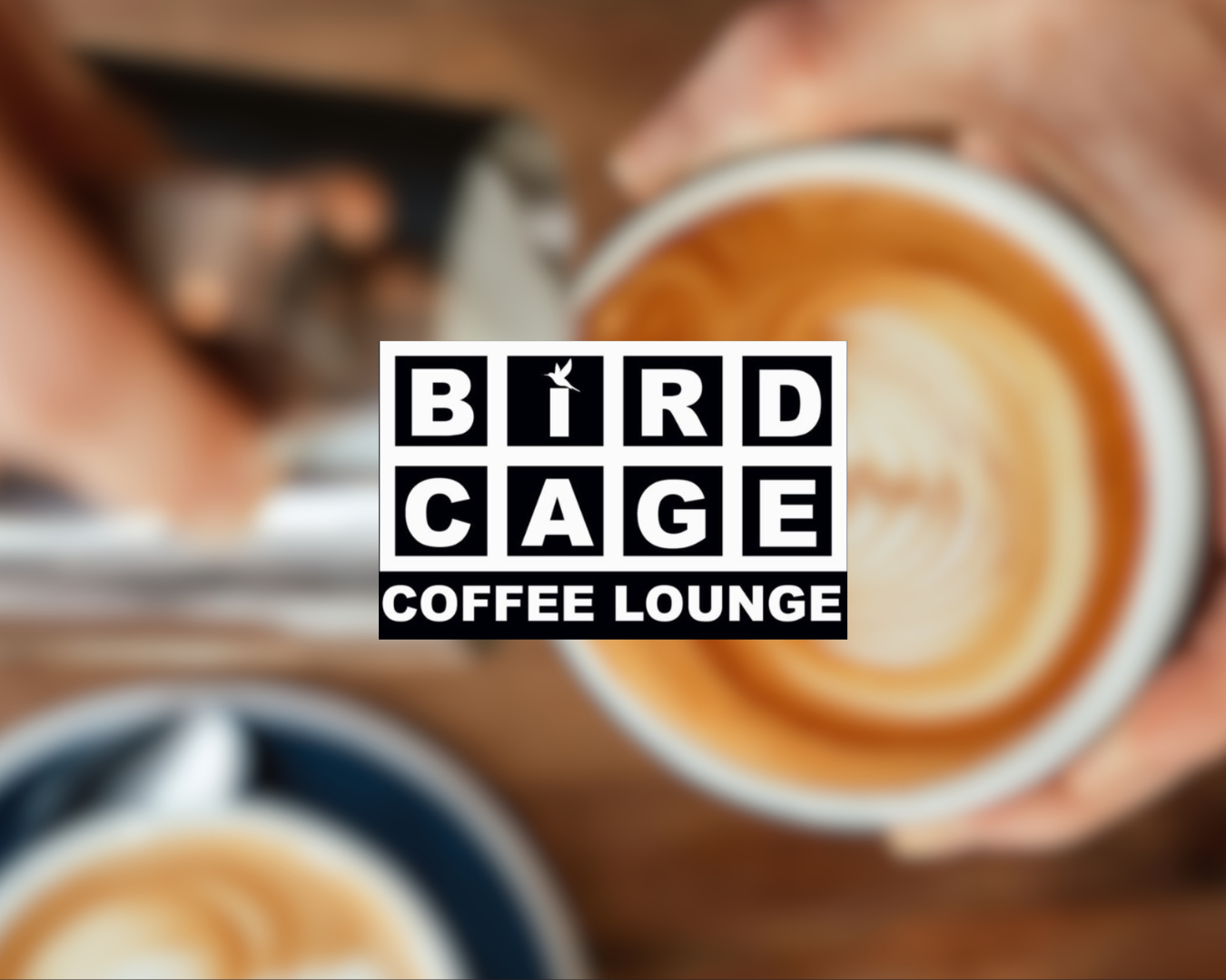 A coffee cup filled with latte art, surrounded by more coffee cups on a wooden table, with a logo for Bird Cage Coffee Lounge overlayed in the center.