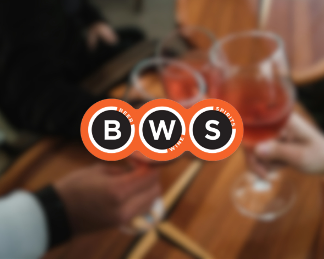 Blurry photo of people holding glasses of red wine at a table with a BWS logo overlay.