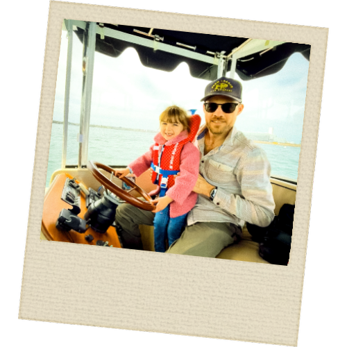 Young child at the helm of a Duffy electric boat on Salem Harbor with family – Slow Wake Society