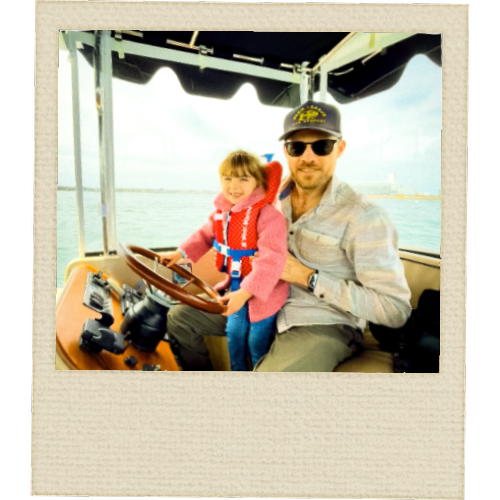 Young child at the helm of a Duffy electric boat on Salem Harbor with family – Slow Wake Society