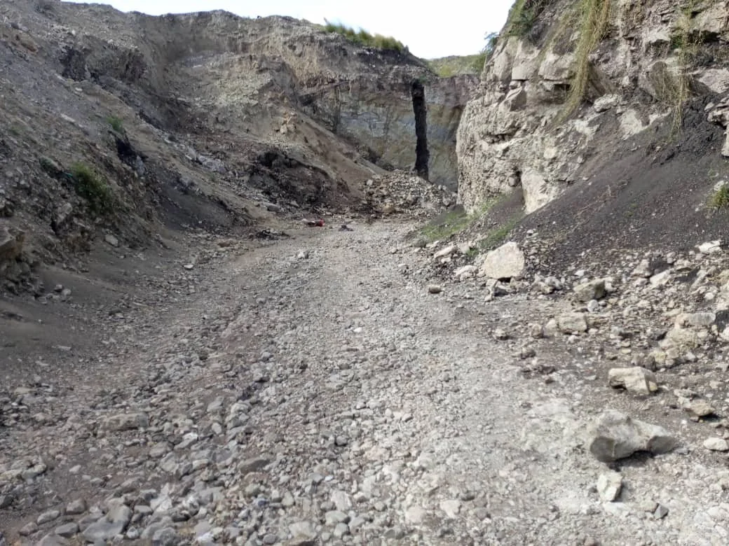 A rocky dirt trail through a canyon or ravine with steep, rugged walls on both sides.
