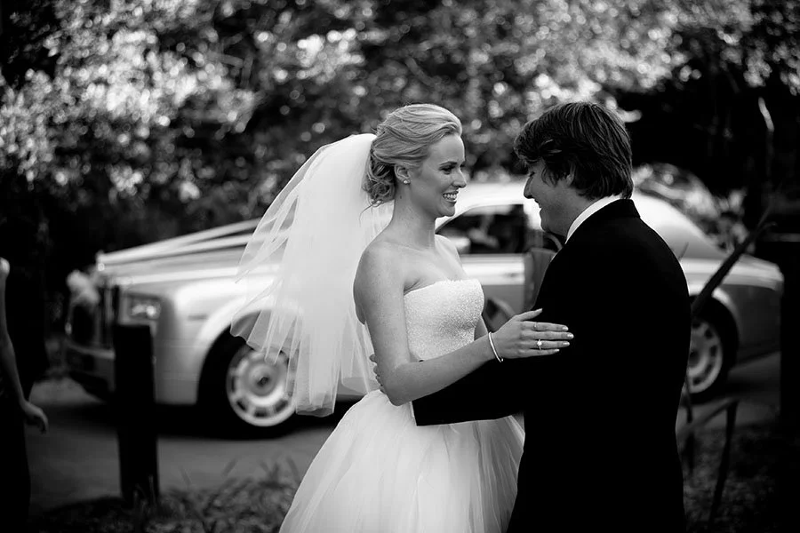 A bride and groom dancing outdoors during a wedding celebration, with a vintage car in the background at Noosa 