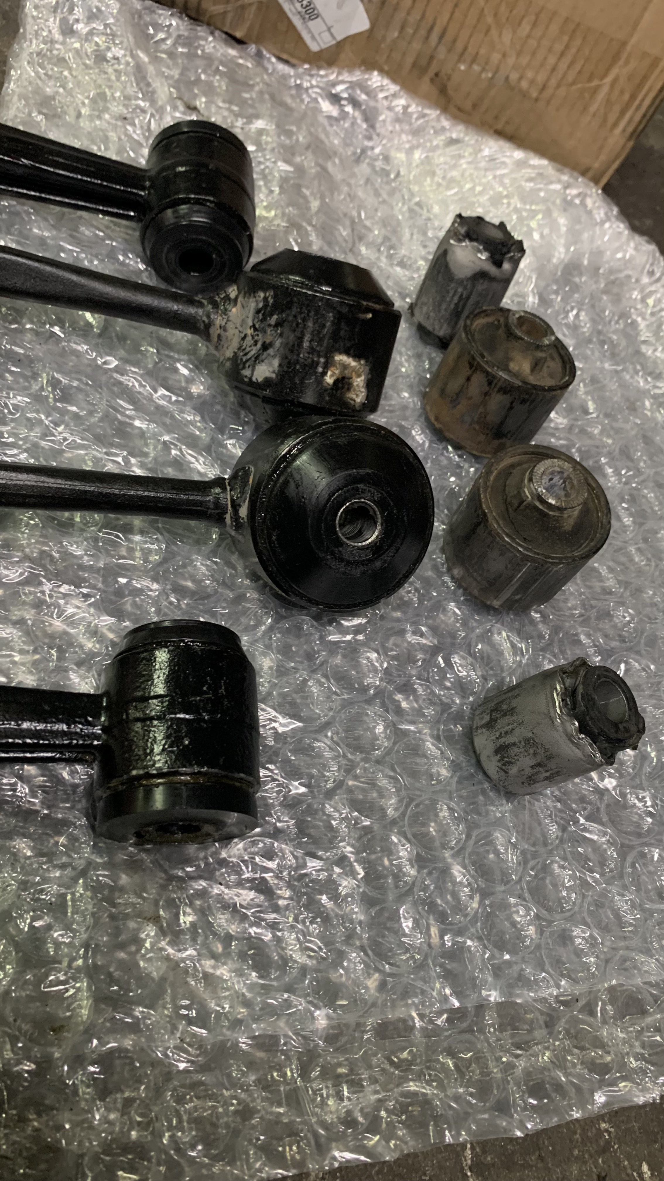 Disassembled automotive suspension components, including control arms and shock absorbers, placed on bubble wrap.