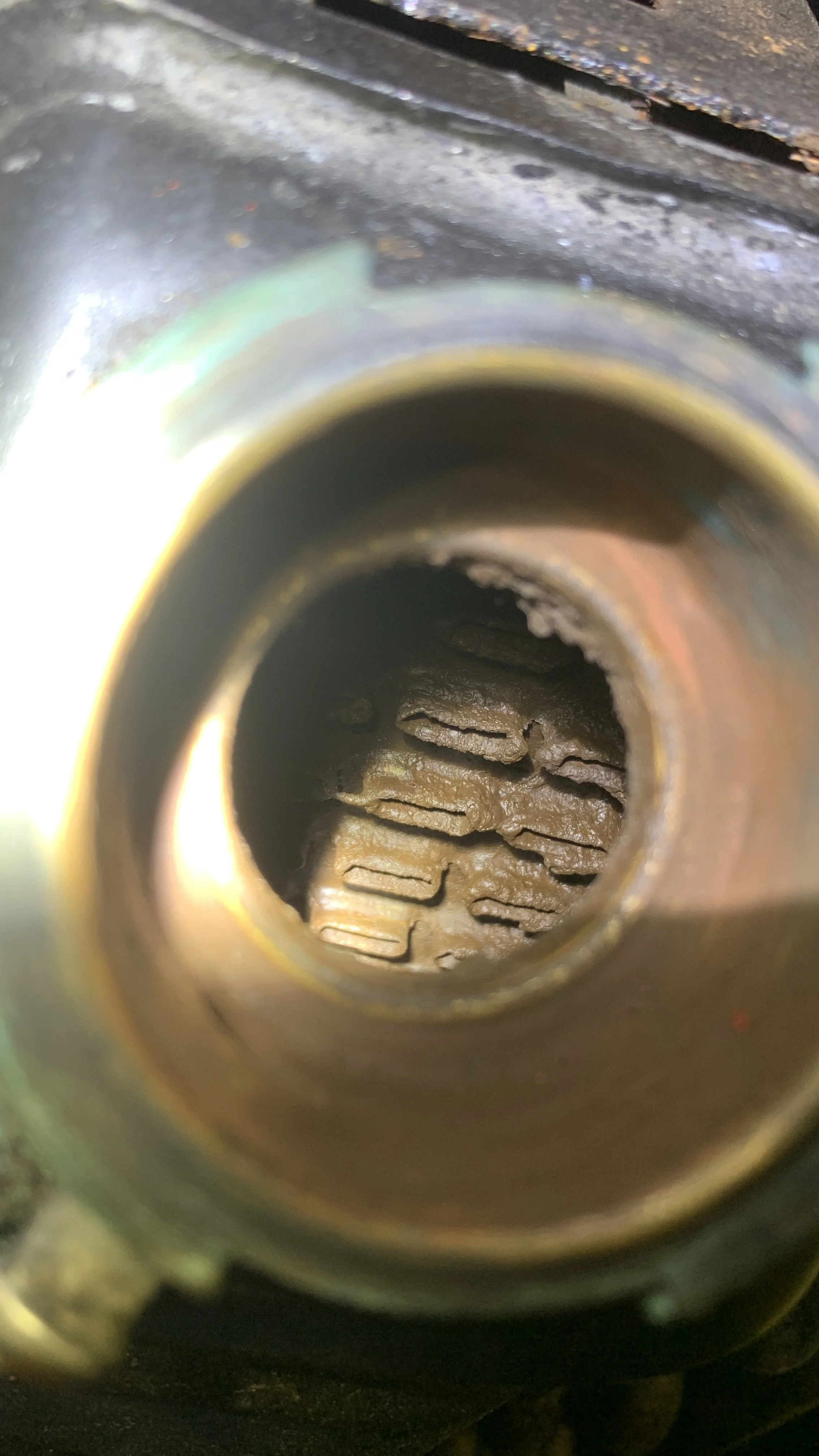 Close-up view inside a rusted engine cylinder, showing carbon deposits on the piston head.