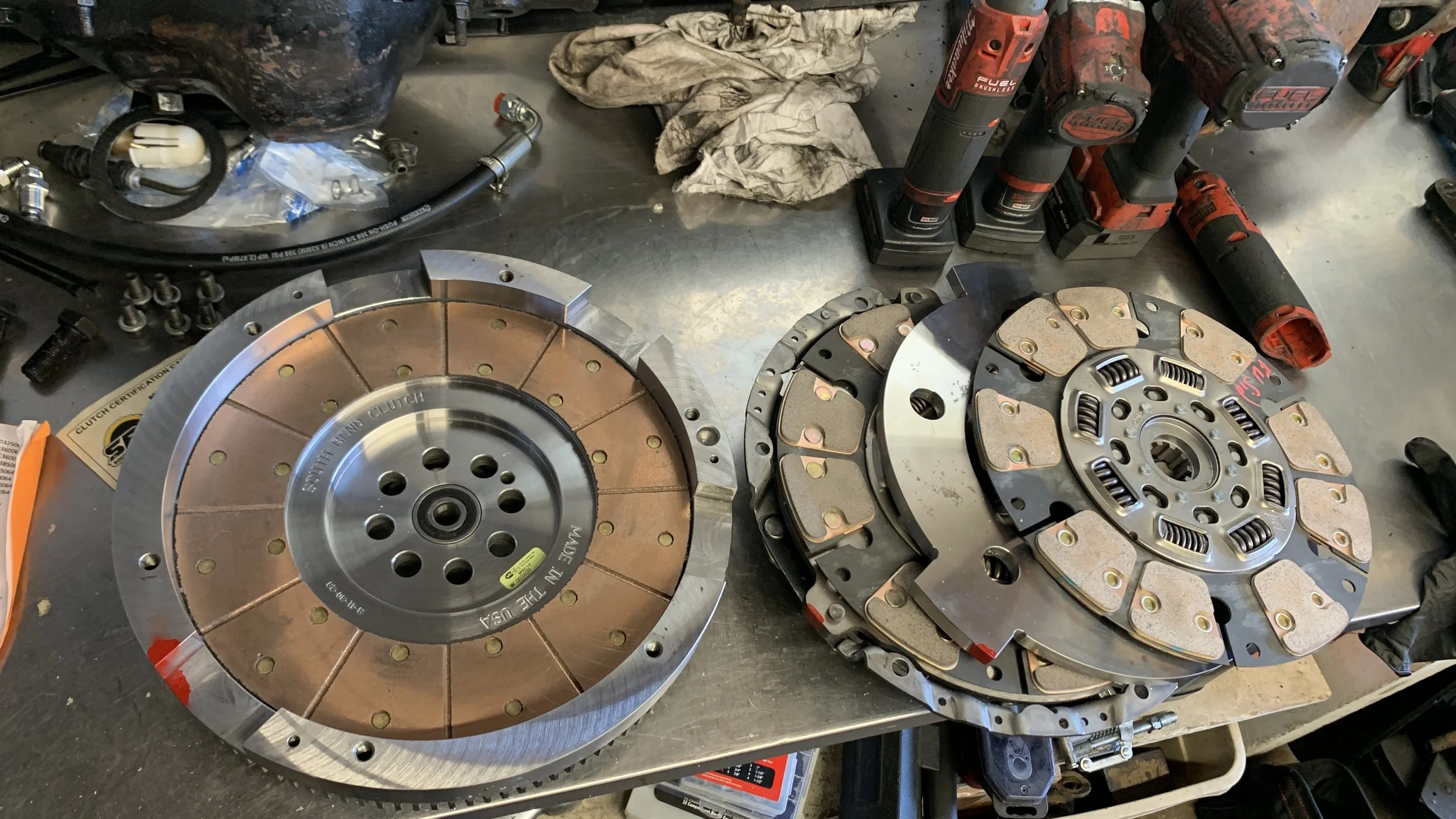 Two clutch assemblies on a workbench, surrounded by tools and parts.