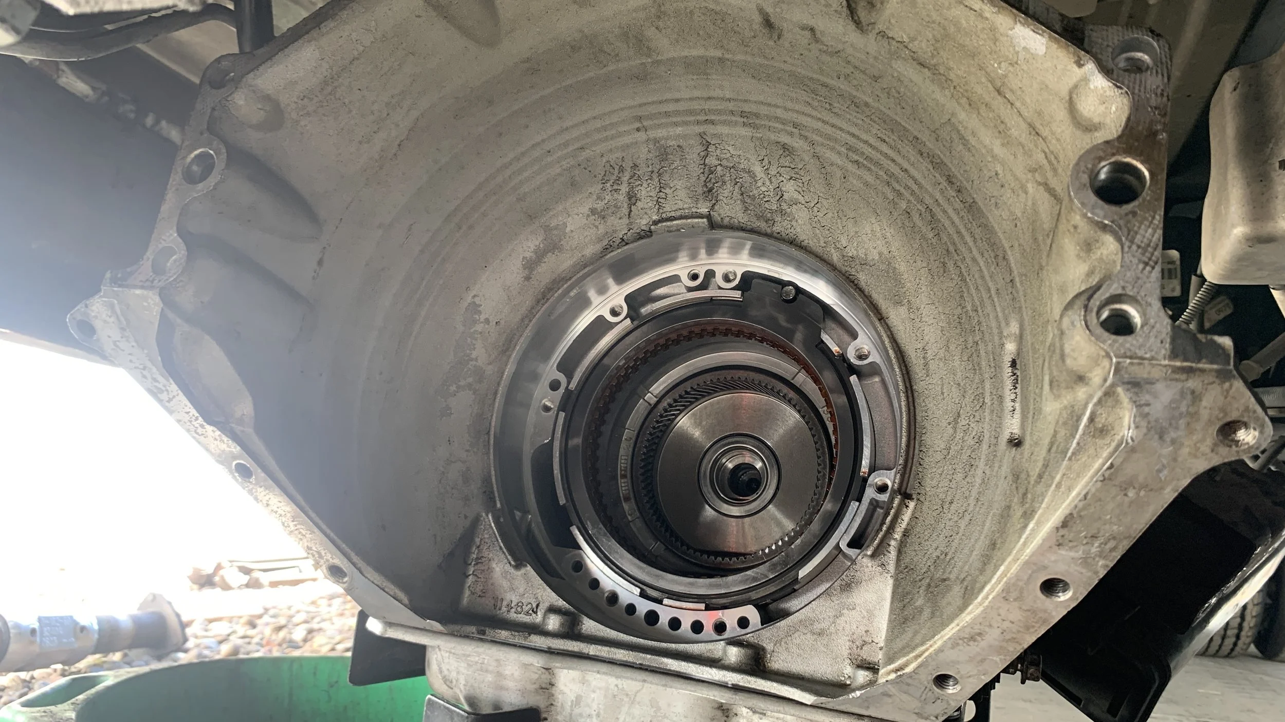 A car transmission housing with the torque converter removed, showing the internal components and flywheel.