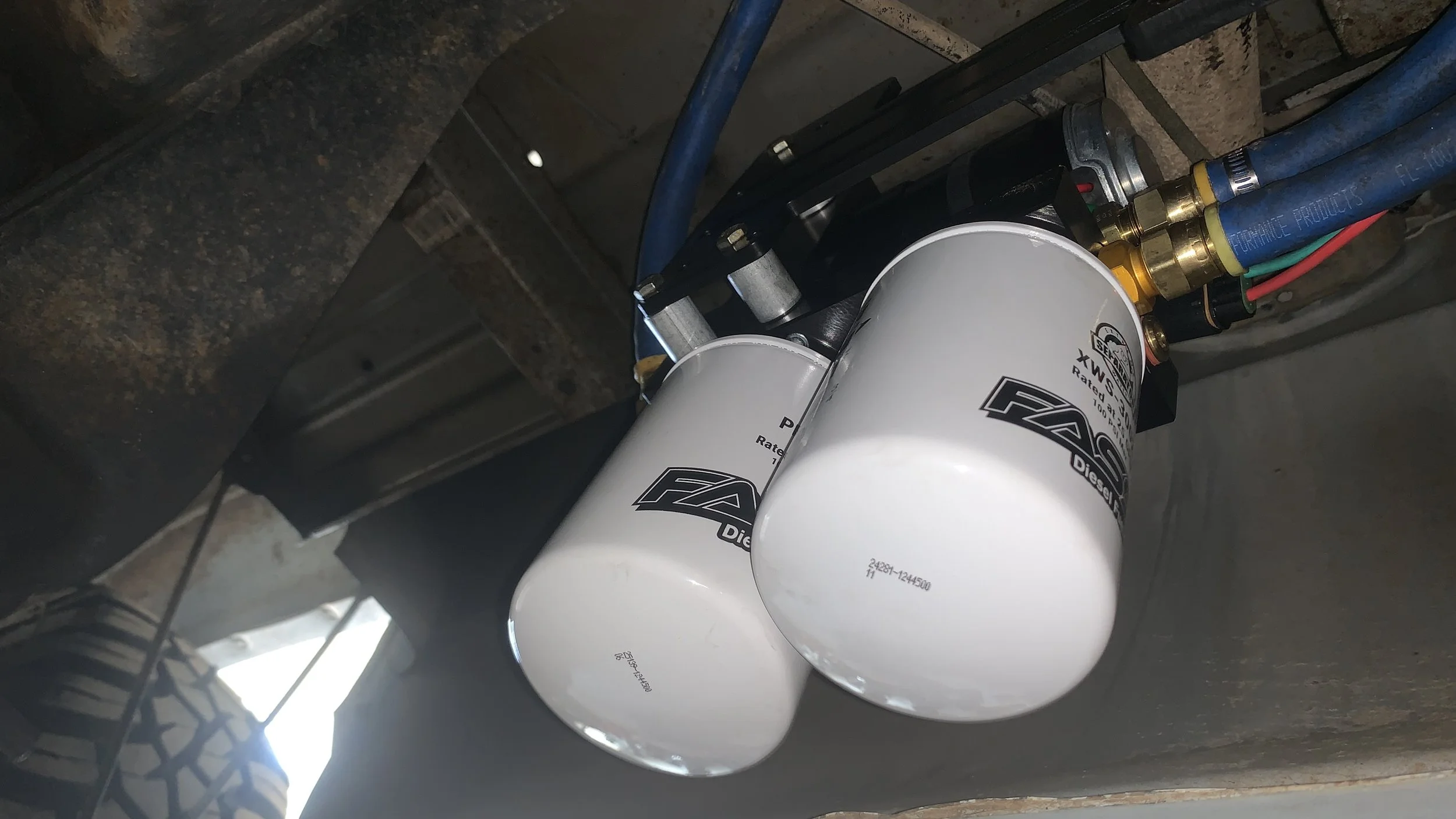 Two white diesel fuel filters installed under a vehicle.