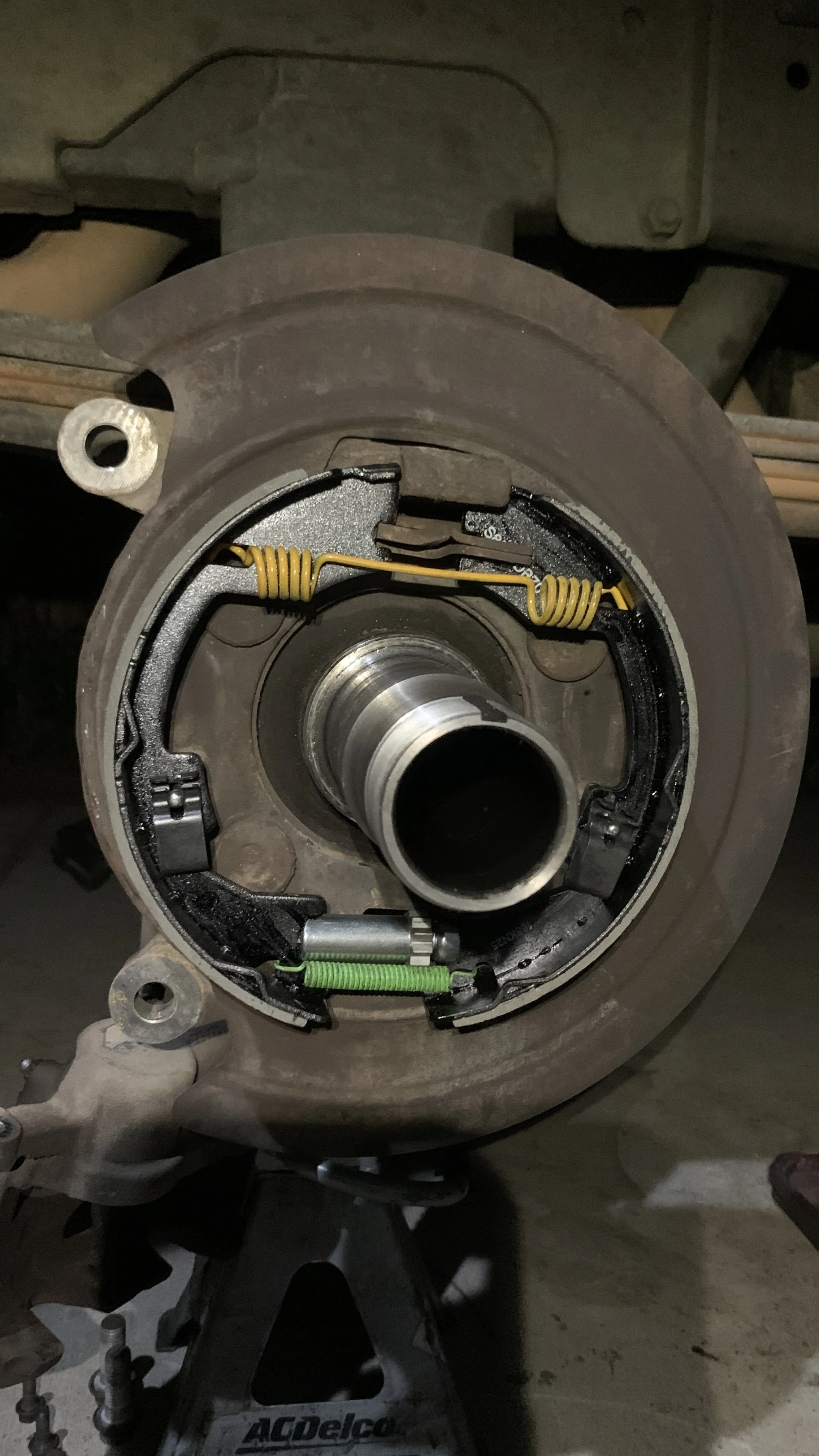 Close-up of a disassembled drum brake assembly mounted on a stand, showing brake shoes, springs, and wheel cylinder components.