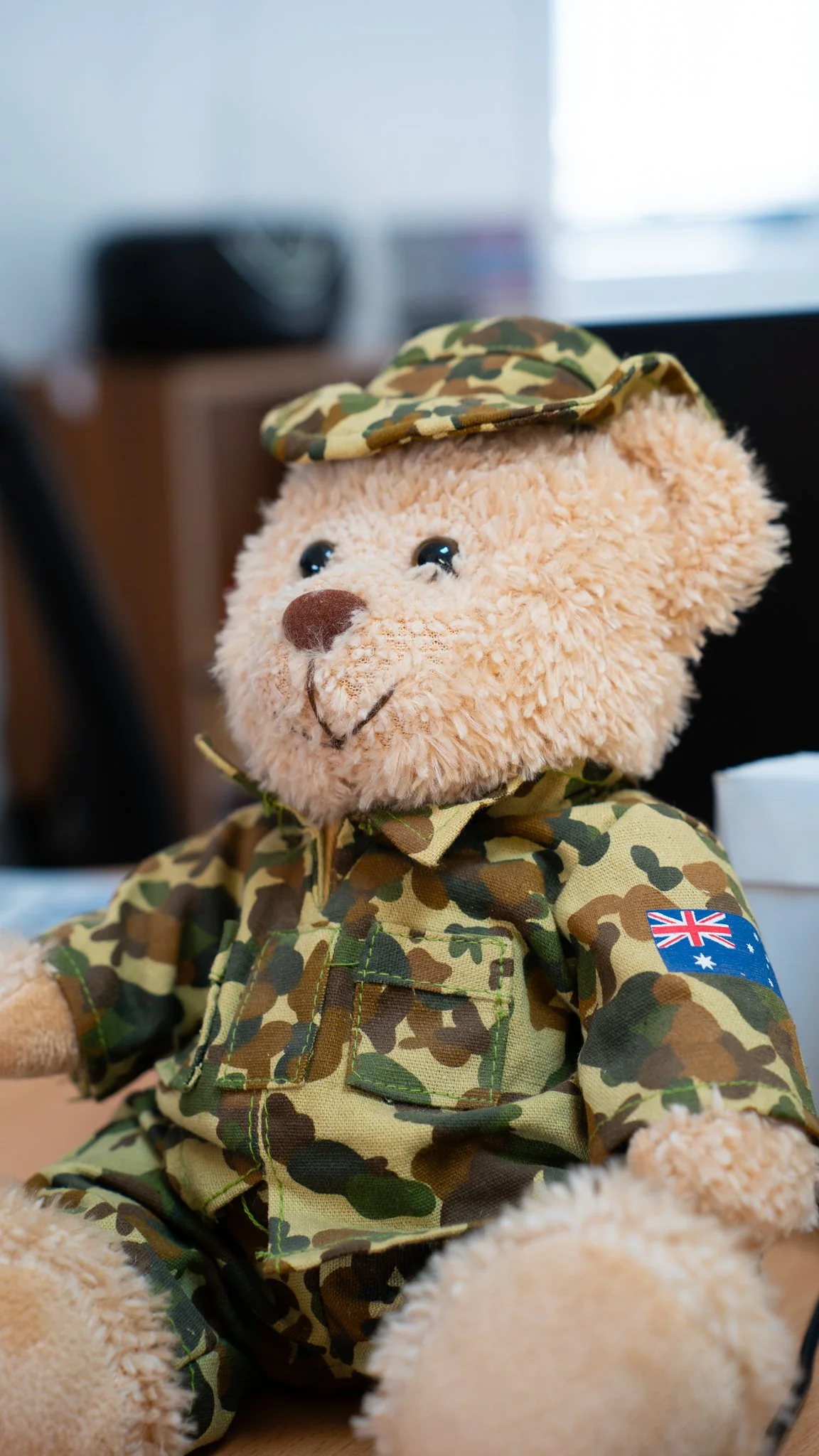A teddy bear dressed in Australian military camouflage uniform with a camouflage cap and Australian flag patch on the sleeve.