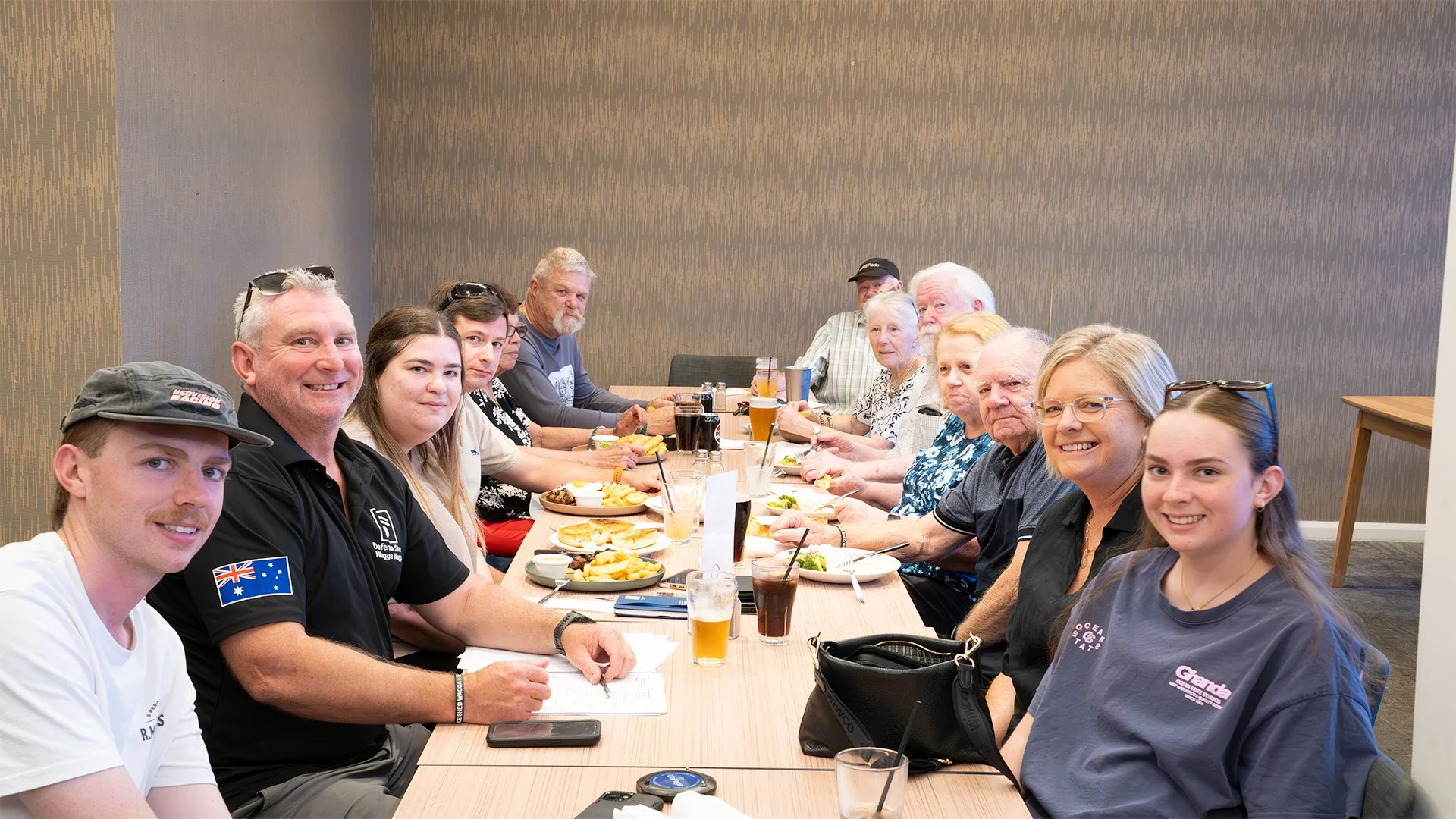 Family and friends gathered around a long dining table in a restaurant, enjoying a meal together.
