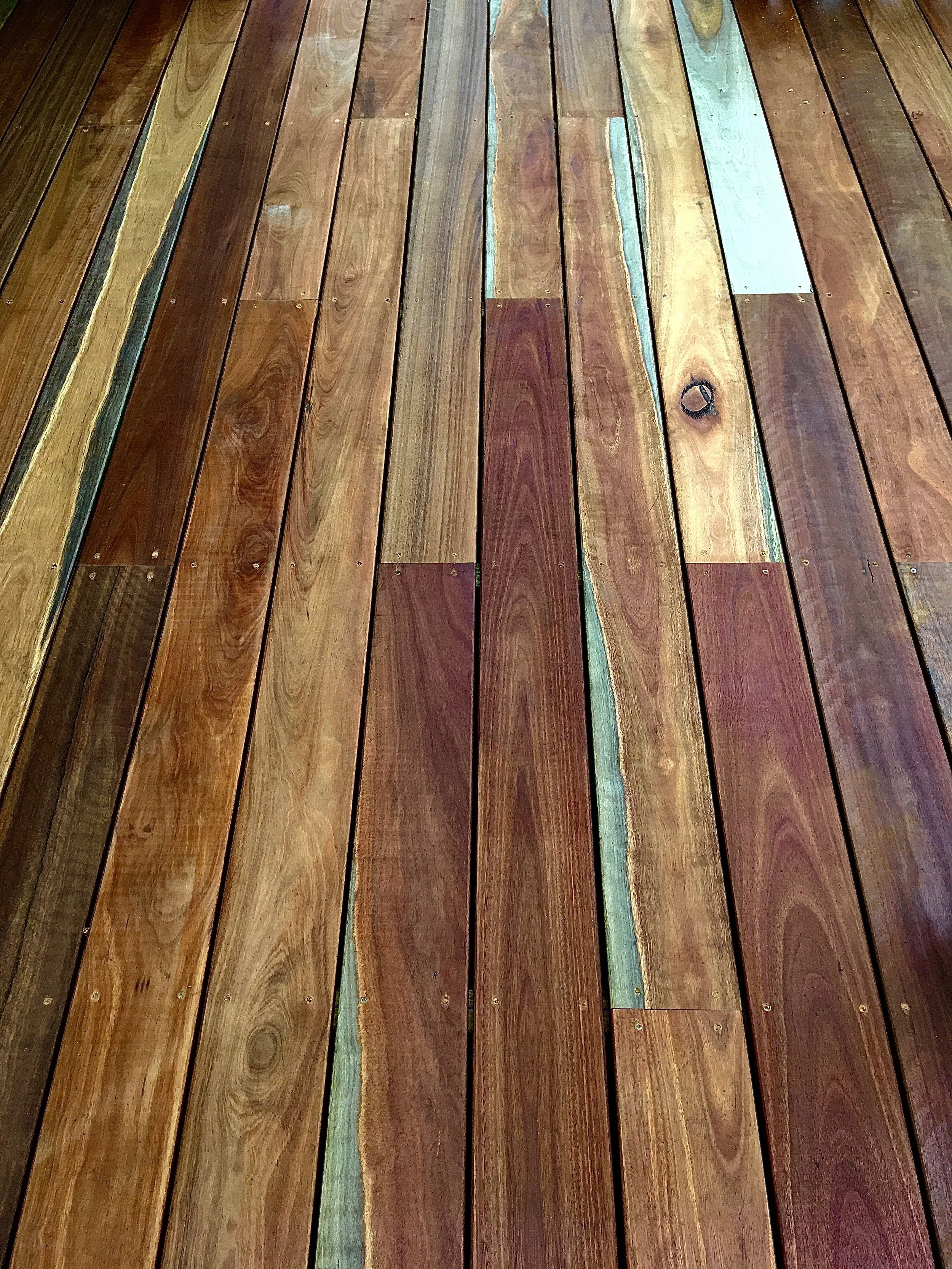 Colorful wooden planks arranged in a row, showing natural wood grain and varying shades of brown, some with painted or stained areas.
